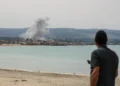 Un hombre de pie en la playa en la zona de Tiro observa el humo que se eleva desde el lugar de un ataque aéreo israelí en la zona de Ras Al-Ain el 12 de mayo de 2026. (KAWNAT HAJU / AFP)