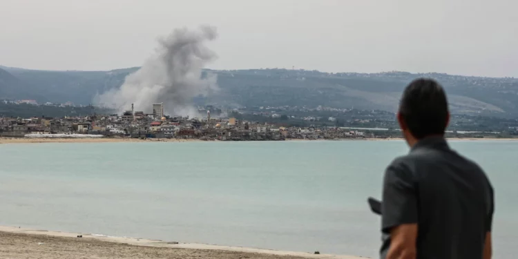 Un hombre de pie en la playa en la zona de Tiro observa el humo que se eleva desde el lugar de un ataque aéreo israelí en la zona de Ras Al-Ain el 12 de mayo de 2026. (KAWNAT HAJU / AFP)