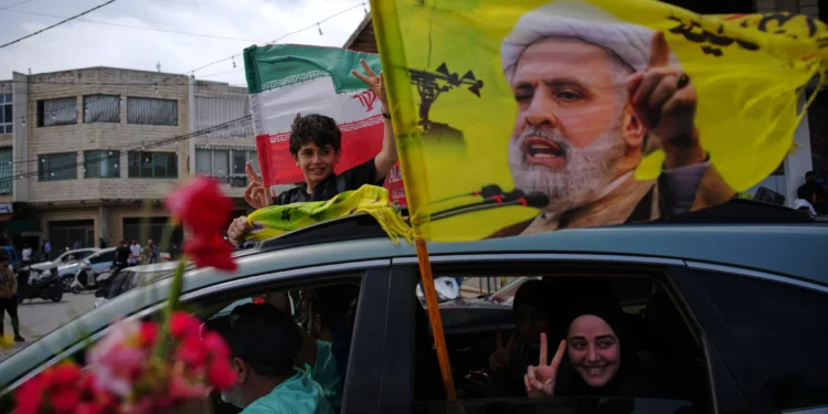 Residentes desplazados ondean una bandera con la imagen del líder de Hezbolá, Naim Qassem, al regresar a sus aldeas tras un alto el fuego entre Israel y Hezbolá, en Zefta, al sur del Líbano, el 17 de abril de 2026. (Foto AP/Hassan Ammar)