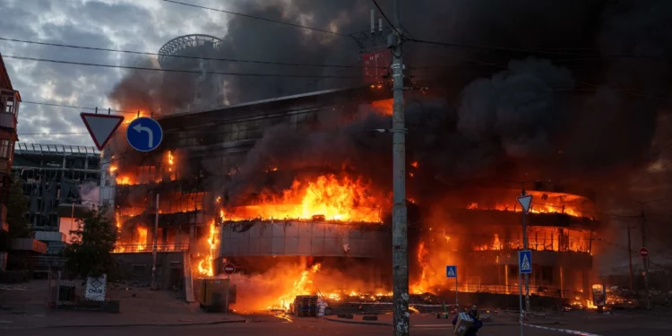 Un hombre saca una caja de un centro comercial en llamas tras un ataque ruso en Kiev, Ucrania, el 24 de mayo de 2026. (Foto AP/Evgeniy Maloletka)