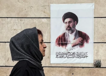Una mujer iraní pasa junto a un cartel con el retrato de Mojtaba Jamenei, el nuevo líder supremo de Irán, en la capital, Teherán, el 13 de abril de 2026. (ATTA KENARE / AFP)