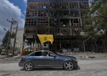 Un hombre con una bandera de Hezbolá pasa en coche junto a un edificio dañado tras el alto el fuego entre Israel y Hezbolá en la localidad de Nabatiyeh, en el sur del Líbano, el 22 de junio de 2026. (Foto AP/Mohammed Zaatari)