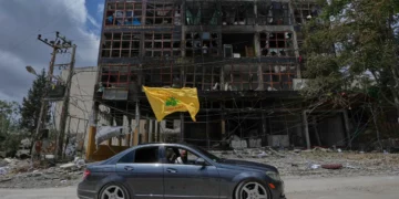 Un hombre con una bandera de Hezbolá pasa en coche junto a un edificio dañado tras el alto el fuego entre Israel y Hezbolá en la localidad de Nabatiyeh, en el sur del Líbano, el 22 de junio de 2026. (Foto AP/Mohammed Zaatari)