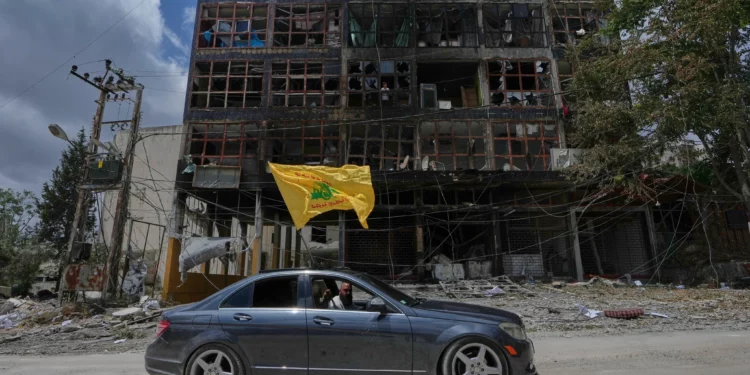 Un hombre con una bandera de Hezbolá pasa en coche junto a un edificio dañado tras el alto el fuego entre Israel y Hezbolá en la localidad de Nabatiyeh, en el sur del Líbano, el 22 de junio de 2026. (Foto AP/Mohammed Zaatari)