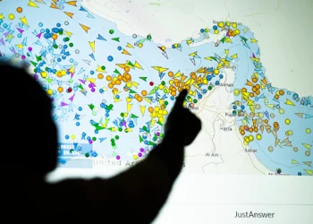Una ilustración fotográfica tomada en Nicosia el 4 de mayo de 2026 muestra a una persona frente a una gran pantalla mostrando los movimientos de embarcaciones en el Estrecho de Ormuz en una página web de rastreo de barcos. (AFP)