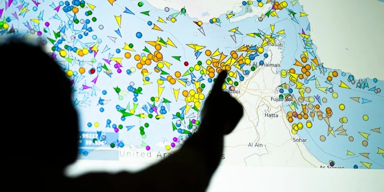 Una ilustración fotográfica tomada en Nicosia el 4 de mayo de 2026 muestra a una persona frente a una gran pantalla mostrando los movimientos de embarcaciones en el Estrecho de Ormuz en una página web de rastreo de barcos. (AFP)