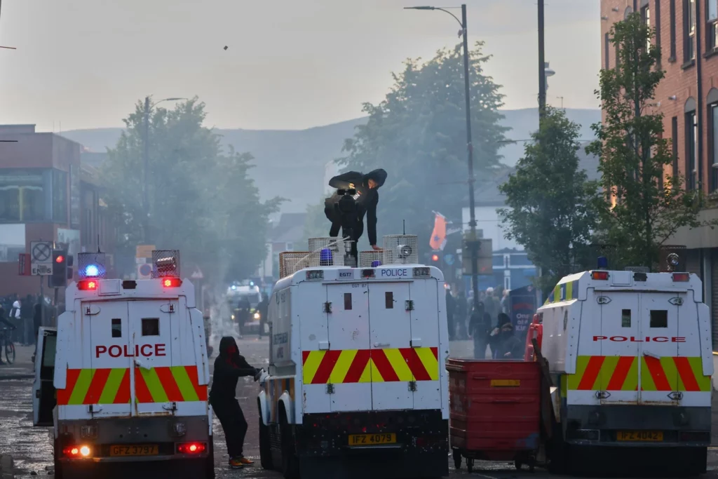 Vehículos policiales son atacados por manifestantes tras un incidente de apuñalamiento en Belfast, el 9 de junio de 2026. (Peter Morrison/AP)