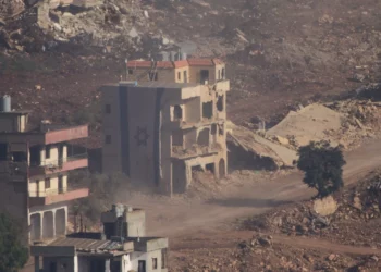 Una bandera israelí cubre parte de un edificio dañado en el sur del Líbano, visto desde el norte de Israel, el 18 de junio de 2026. (Foto AP/Ariel Schalit)