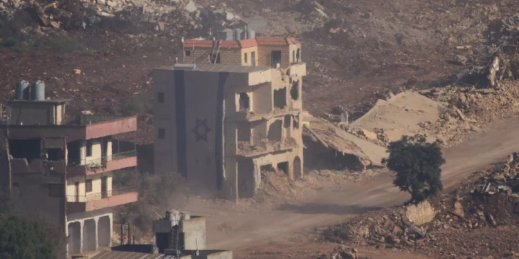 Una bandera israelí cubre parte de un edificio dañado en el sur del Líbano, visto desde el norte de Israel, el 18 de junio de 2026. (Foto AP/Ariel Schalit)