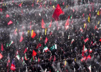 Se rocía agua sobre los dolientes para refrescar a la multitud mientras se izan banderas iraníes, pakistaníes y de otros países durante las ceremonias fúnebres, que se prolongan durante varios días, en memoria del líder supremo iraní asesinado, el ayatolá Alí Jamenei, y de los miembros de su familia, frente a la Gran Mezquita Mosalla del Imán Jomeini, en Teherán (Irán), el 5 de julio de 2026. (Foto AP/Altaf Qadri)