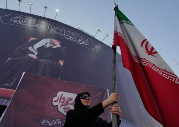 Una mujer partidaria del Gobierno sostiene una bandera iraní bajo una pancarta en la que aparece un retrato del líder supremo asesinado, el ayatolá Alí Jamenei, en una plaza del centro de Teherán, Irán, el 30 de junio de 2026. (Foto AP/Vahid Salemi)