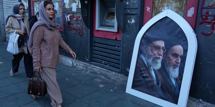 Los peatones pasan junto a un cartel en el que aparecen el líder supremo iraní asesinado, el ayatolá Ali Jamenei (a la izquierda), y el difunto fundador de la revolución, el ayatolá Jomeini, en una acera de la plaza de la Revolución Islámica de Teherán (Irán), el domingo 14 de junio de 2026. (AP/Vahid Salemi)