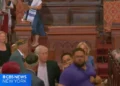 El sospechoso Larry Montes (vestido de azul) fue visto siendo escoltado fuera de la Sinagoga Central de Manhattan tras presuntamente atacar a los fieles el 14 de agosto de 2026. (Captura de pantalla/CBS Nueva York)