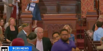 El sospechoso Larry Montes (vestido de azul) fue visto siendo escoltado fuera de la Sinagoga Central de Manhattan tras presuntamente atacar a los fieles el 14 de agosto de 2026. (Captura de pantalla/CBS Nueva York)