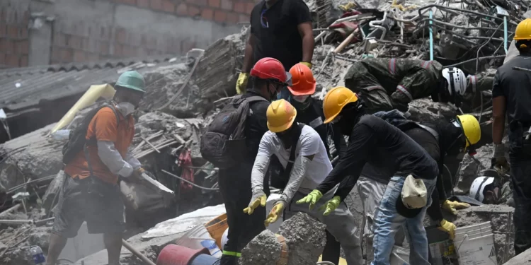 Equipos de rescate y voluntarios buscan supervivientes entre los escombros de un edificio derrumbado tras el terremoto que sacudió Cali, Colombia, el 12 de agosto de 2026. (Raul ARBOLEDA/AFP)