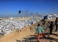 ARCHIVO) Unos niños hacen volar una cometa con el humo que se eleva del refugio de Gath, que alberga a palestinos desplazados, tras un ataque aéreo israelí en el oeste de Jan Yunis, en el sur de la Franja de Gaza, el 31 de enero de 2026. (Bashar Taleb/AFP)