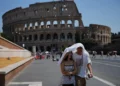 Turistas se resguardan del sol mientras caminan frente al antiguo Coliseo de Roma, 1 de agosto de 2026. (Foto AP/Alessandra Tarantino)