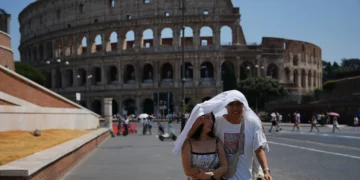 Turistas se resguardan del sol mientras caminan frente al antiguo Coliseo de Roma, 1 de agosto de 2026. (Foto AP/Alessandra Tarantino)