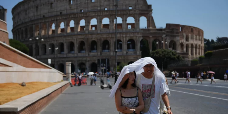 Turistas se resguardan del sol mientras caminan frente al antiguo Coliseo de Roma, 1 de agosto de 2026. (Foto AP/Alessandra Tarantino)