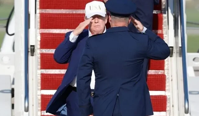 El presidente de Estados Unidos, Donald Trump (izquierda), es recibido por el coronel de la Fuerza Aérea Christopher M. Robinson, comandante del 89.º Ala de Transporte Aéreo, tras bajar las escaleras del Air Force One a su llegada a la Base Conjunta Andrews, Maryland, el 9 de agosto de 2026. (Foto AP/Luis M. Alvarez)