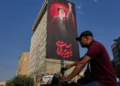 Un hombre pasa en su motocicleta junto a una valla publicitaria con un mensaje en persa que dice: “Debemos levantarnos” y una imagen del difunto líder supremo iraní, el ayatolá Alí Jamenei, en Teherán, Irán, el 15 de agosto de 2026. (AP/Vahid Salemi)