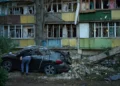 Un residente local observa el interior de un automóvil destruido junto a edificios residenciales gravemente dañados tras un ataque ruso ocurrido durante la noche en Kiev, Ucrania, el 20 de agosto de 2026. (Foto AP/Francisco Seco)