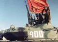 Soldados soviéticos que regresaban a casa con su regimiento de tanques saludaron a una tribuna de honor mientras comenzaba la retirada parcial de las tropas de Moscú en Afganistán en Shindand, Afganistán, el 17 de octubre de 1986. (Foto AP/Carol J. Williams)
