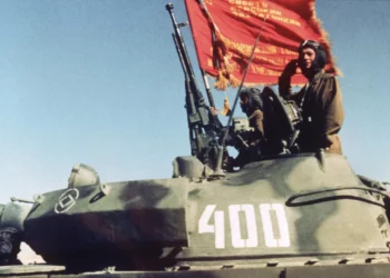 Soldados soviéticos que regresaban a casa con su regimiento de tanques saludaron a una tribuna de honor mientras comenzaba la retirada parcial de las tropas de Moscú en Afganistán en Shindand, Afganistán, el 17 de octubre de 1986. (Foto AP/Carol J. Williams)