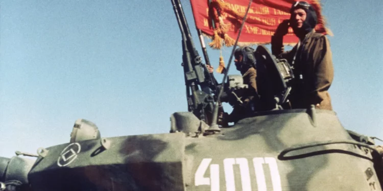 Soldados soviéticos que regresaban a casa con su regimiento de tanques saludaron a una tribuna de honor mientras comenzaba la retirada parcial de las tropas de Moscú en Afganistán en Shindand, Afganistán, el 17 de octubre de 1986. (Foto AP/Carol J. Williams)