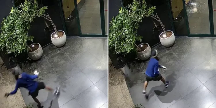 Un asaltante enmascarado fue captado por las cámaras de vigilancia lanzando un ladrillo contra las puertas de cristal de las oficinas del Canal 12 en Tel Aviv, en la madrugada del 28 de julio de 2026. (Canal 12 vía X)