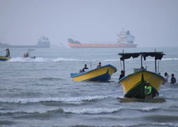 Pequeñas embarcaciones bordean la costa mientras buques de carga y otros barcos comerciales parecen estar anclados en el estrecho de Ormuz, frente a Bandar Abbas, Irán, el 27 de julio de 2026. (Razieh Poudat/ISNA vía AP)