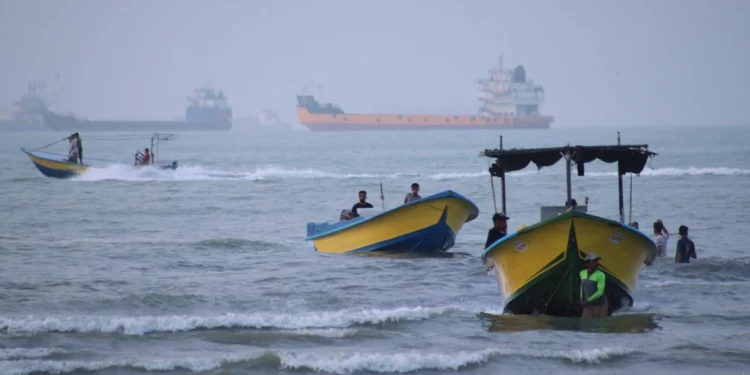 Pequeñas embarcaciones bordean la costa mientras buques de carga y otros barcos comerciales parecen estar anclados en el estrecho de Ormuz, frente a Bandar Abbas, Irán, el 27 de julio de 2026. (Razieh Poudat/ISNA vía AP)