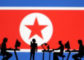 En esta ilustración, tomada el 19 de julio de 2023, se ven miniaturas de personas con ordenadores frente a la bandera de Corea del Norte. Reuters/Dado Ruvic/Ilustración