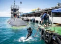 Buzos de la Marina de Estados Unidos y de Australia trabajan bajo el casco del USS Vermont durante un periodo de mantenimiento.