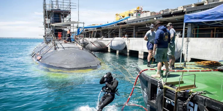 Buzos de la Marina de Estados Unidos y de Australia trabajan bajo el casco del USS Vermont durante un periodo de mantenimiento.