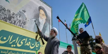 Un clérigo chiita armado viaja en un vehículo militar frente a una valla con la imagen del ayatolá Ruhollah Jomeini durante el desfile «Janfada» en Teherán, Irán, el 18 de septiembre de 2026.
