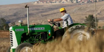 Man drivers tractor on Israeli kibbutz (illustrative)