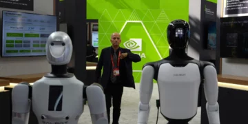 A worker stands near robots at the Nvidia booth during the China International Supply Chain Expo in Beijing on June 22, 2026. (Ng Han Guan/AP)