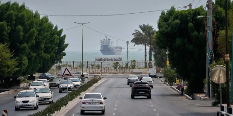 El tráfico circula por una avenida mientras un buque mercante permanece anclado en el estrecho de Ormuz frente a Bandar Abbas, Irán, el 7 de septiembre de 2026.