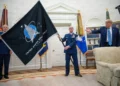 El general estadounidense John “Jay” Raymond, a la izquierda, y el jefe maestro sargento Roger Towberman sostienen la bandera de la Fuerza Espacial mientras el presidente Donald Trump la señala en el Despacho Oval de la Casa Blanca, en Washington, el 15 de mayo de 2020.