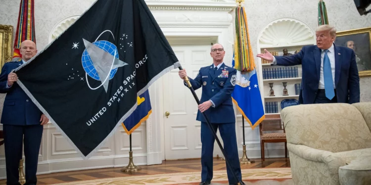 El general estadounidense John “Jay” Raymond, a la izquierda, y el jefe maestro sargento Roger Towberman sostienen la bandera de la Fuerza Espacial mientras el presidente Donald Trump la señala en el Despacho Oval de la Casa Blanca, en Washington, el 15 de mayo de 2020.