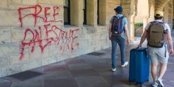 Estudiantes caminan junto a grafitis cerca de la oficina del presidente de Stanford, Richard Saller, en Palo Alto, California, el 5 de junio de 2024.