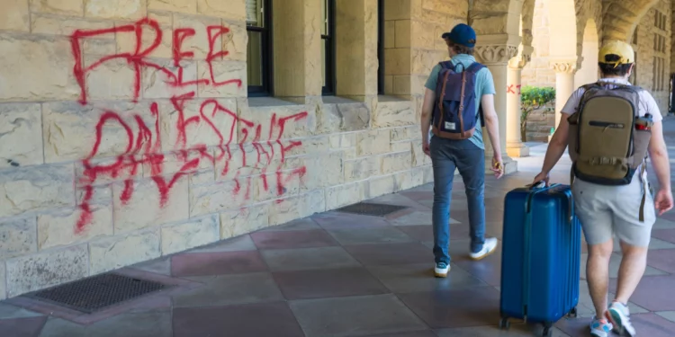 Estudiantes caminan junto a grafitis cerca de la oficina del presidente de Stanford, Richard Saller, en Palo Alto, California, el 5 de junio de 2024.