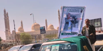 Un hombre junto al retrato de un combatiente hutí durante un cortejo fúnebre en Saná, Yemen.
