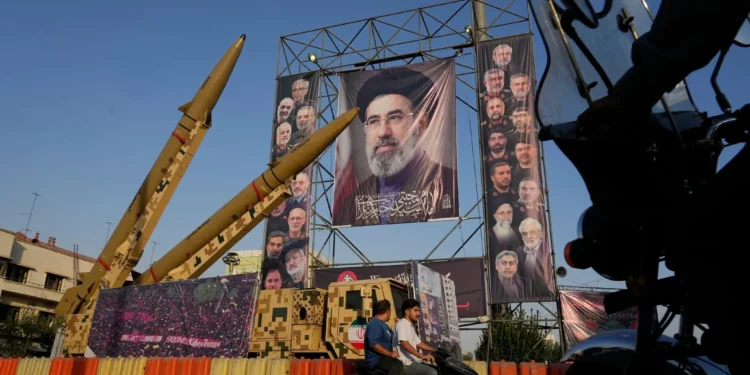 Motorbikes drive past Iranian missiles and banners showing portraits of the Iranian Supreme Leader Ayatollah Mojtaba Khamenei, center, and the late armed forces commanders and nuclear scientists, who were killed in Israeli and US strikes, at Baharestan Square, in Tehran, September 28, 2026. (AP/Vahid Salemi)