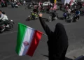 Una mujer sostiene una bandera iraní y corea consignas durante un desfile estatal de motocicletas en Teherán, el 25 de septiembre de 2026.