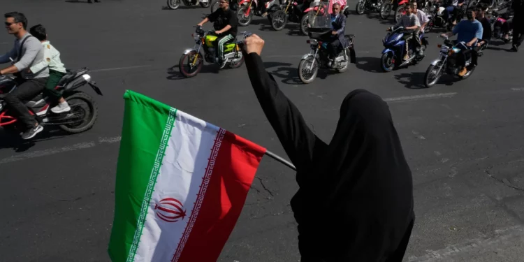 Una mujer sostiene una bandera iraní y corea consignas durante un desfile estatal de motocicletas en Teherán, el 25 de septiembre de 2026.