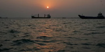 El sol se pone sobre buques comerciales fondeados en el estrecho de Ormuz frente a Bandar Abbas, Irán, con la ciudad al fondo, 6 de septiembre de 2026.