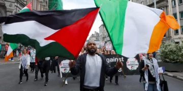 Una persona sostiene banderas de Irlanda y Palestina durante una protesta en Dublín relacionada con la guerra en Gaza.
