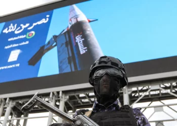 Un agente de seguridad vigila frente a una gran imagen de un misil con la palabra Palestina durante una manifestación hutí en Saná.